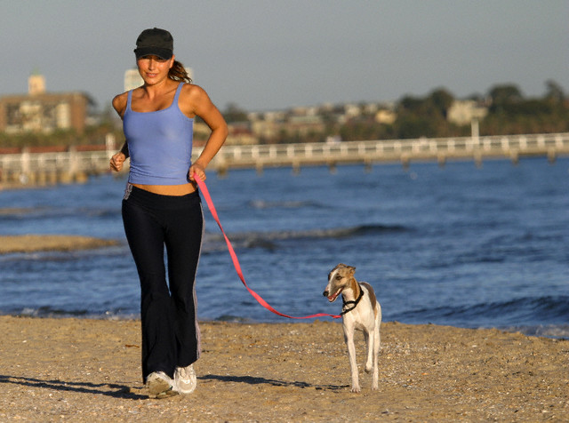 Woman Jogging with Dog on Beach